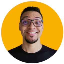 Foto de Mayk Brito sorrindo, usando óculos e camisa preta, barba e fundo amarelo.
